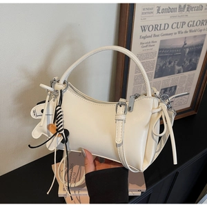 Detail of white minimalist handbag with side bow tie and cute cow pendant charm
