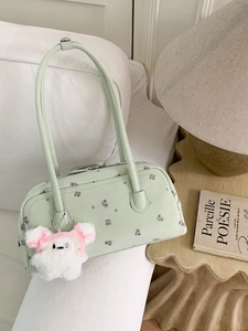 Chic mint green floral shoulder bag with plush rabbit charm on a stylish white sofa