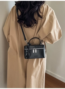 Detail showing back view of black box cross-body bag worn by a model in minimalist setting