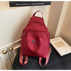 Dettaglio dello zaino multifunzionale in nylon bordeaux su uno sgabello a righe elegante