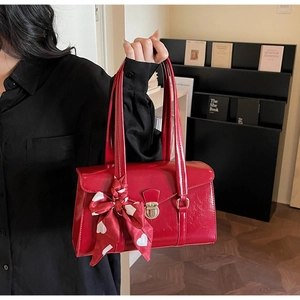 Détail du sac à main de mariée rouge avec finition brillante, boucle dorée et foulard en soie