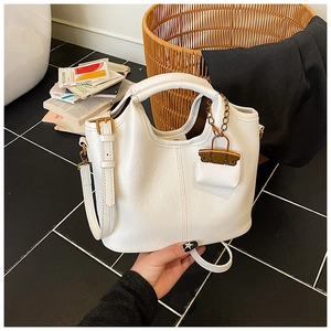 Détail d'un sac à main blanc en similicuir avec pendentif doré et poignées solides