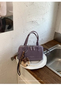 Détail du sac Boston violet mat avec zips argentés, ours en peluche et sangle léopard
