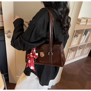 Détail d'un sac à bandoulière en cuir verni marron foncé avec foulard et fermoir doré