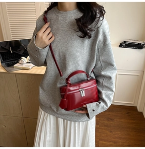Detail of red glossy box bag with silver zippers and detachable shoulder strap