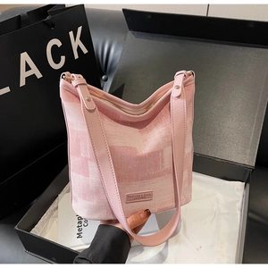 Dettaglio della borsa a secchiello in tela con cuciture in pelle rosa e logo
