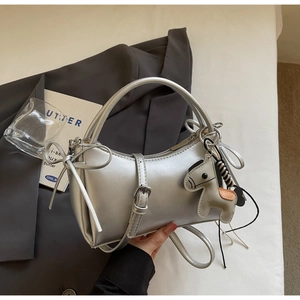 Detail of silver half-moon handbag featuring a side bow and a horse charm accessory