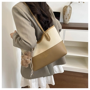 Dettaglio della borsa tote in tela con finiture in pelle marrone e ciondolo orso