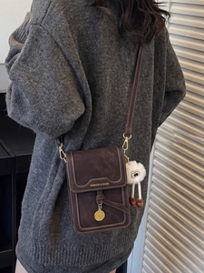 Brown vintage faux leather crossbody bag with golden metal charm and plush toy decor