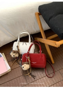 Détail d'un sac Boston cylindrique avec fermeture éclair et pendentif ours de collection