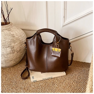 Détail d'un sac à main en cuir marron foncé avec coutures décoratives et mini breloque