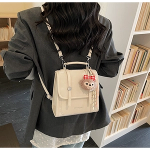 Detail of cream-white PU leather backpack featuring dual straps and ShellieMay plush charm