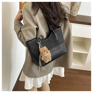 Borsa tote nera alla moda con ciondolo a forma di cane di peluche indossata da una modella