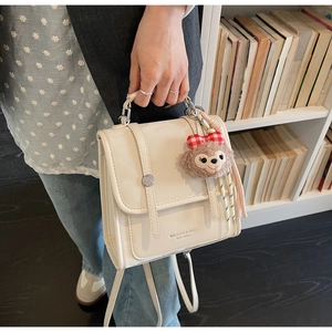 Detail of a beige PU leather vintage backpack with a plush bear charm and handle