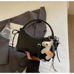 Close-up of black crescent leather handbag featuring a stylish horse charm and buckle detail