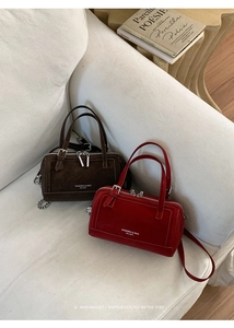 Gros plan de sacs Boston en cuir mat marron et rouge sur un canapé minimaliste