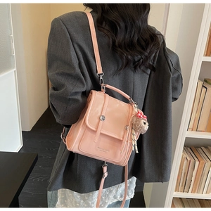 Pink synthetic leather backpack with front flap, metal snap, and plush doll accessory