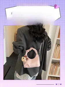 Pink pleated dumpling bag with cute plush bear charm and chain strap on female model