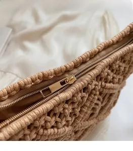 Close-up of golden metal zipper and smooth inner lining on beige woven shoulder bag