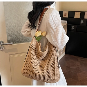 Detail of hand-woven beige crochet tote bag with brown leather strap and hollow pattern