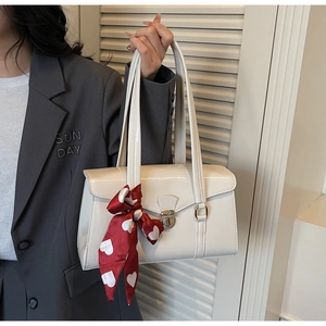 Détail du sac à main beige rectangulaire en similicuir avec fermoir argenté et foulard