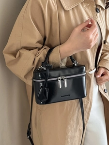 Minimalist black box handbag with silver zipper and shoulder strap on female model