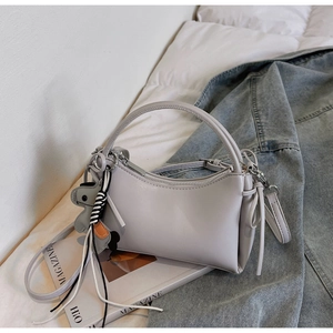 Detailed view of grey minimalist handbag with ring handle and cute rabbit charm