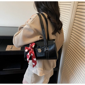 Détail d'un sac à bandoulière en cuir noir mat avec boucle argentée et foulard à cœurs