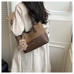 Dettaglio di una borsa tote patchwork marrone con trame in tela e pelle di qualità