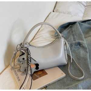 Detail view of light grey PU leather crescent handbag with shoulder strap and pony charm