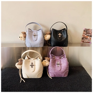 Detail view of four leather bucket bags in various colors with bear charms and metal locks