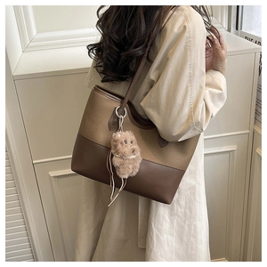 Dettaglio della grande borsa tote in tela e pelle marrone con ciondolo a forma di orsetto