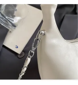 Detail of silver metal chain strap and luxury hardware on the off-white crescent bag