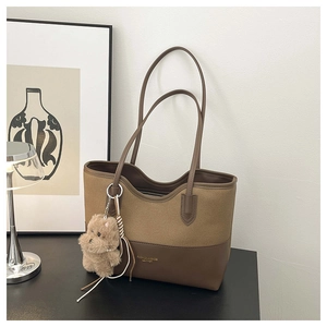Dettaglio della borsa tote in tela con finiture in pelle e ciondolo a forma di orso