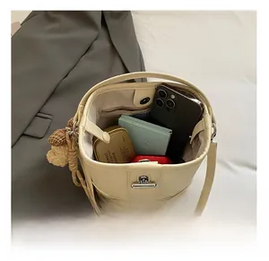 Top view showing the large internal capacity of the beige bucket bag with a bear charm