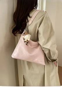 Borsa hobo rosa a pieghe con ciondolo di peluche portata a spalla dalla modella