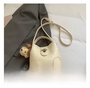 Detail of cream bucket bag with silver twist lock and cute plush bear charm decoration