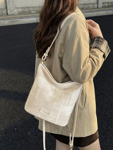 Borsa a secchiello strutturata color crema con tracolla regolabile indossata da una modella