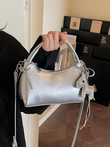 Chic silver metallic handheld crossbody bag with horse charm in minimalist setting