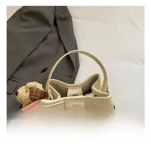 Detail of cream bucket bag showing metal twist lock and cute teddy bear charm