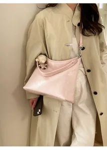Borsa a mezzaluna rosa lucida con perline decorative indossata su un trench coat