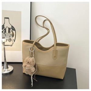 Dettaglio della borsa tote in tela kaki e pelle con un grazioso ciondolo a orsetto