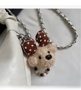 Detail of teddy plush bear bag charm with polka dot bow on white leather purse