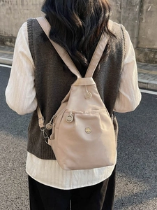Zaino minimalista in nylon beige con tasche multistrato mostrato sulla modella