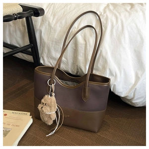 Dettaglio della borsa tote in tela e pelle con logo oro, fodera a righe e ciondolo a cane
