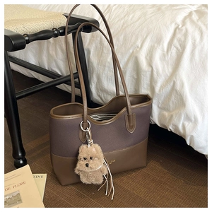 Dettaglio borsa tote in tela con finiture in pelle e ciondolo a forma di cane