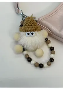 Dettaglio di un ciondolo di peluche con cappello a maglia su una borsa rosa