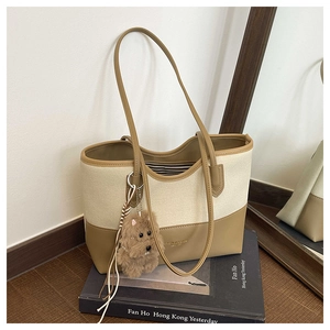 Dettaglio della borsa tote in tela con finiture in pelle kaki e ciondolo a cane di peluche