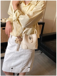 Close-up of cream bucket bag with silver twist lock and cute plaid bear charm