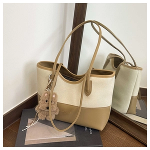 Dettaglio della borsa tote in tela con finiture in pelle, logo e ciondolo a peluche